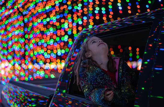 Little girl looking at magic of lights show out of car window