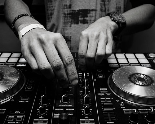 Hands turning buttons on DJ board.