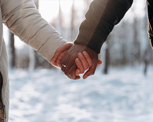 Two people holding hands in the snow.